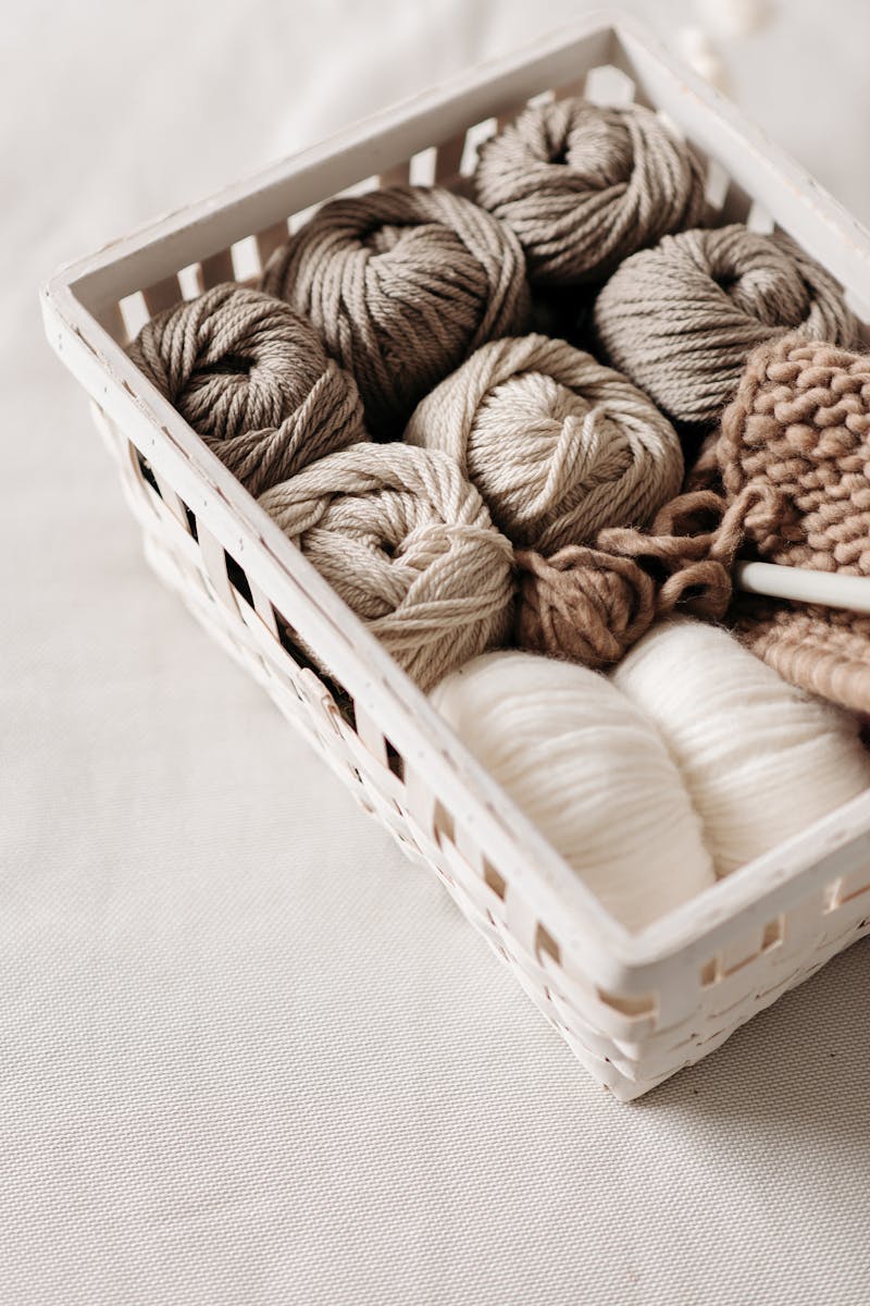 Basket filled with various yarn balls in earthy tones, ready for knitting projects.